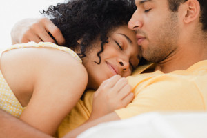 Couple cuddling on bed --- Image by © JGI/Jamie Grill/Blend Images/Corbis